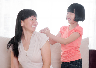 Asian child doing shoulder massage to her mother