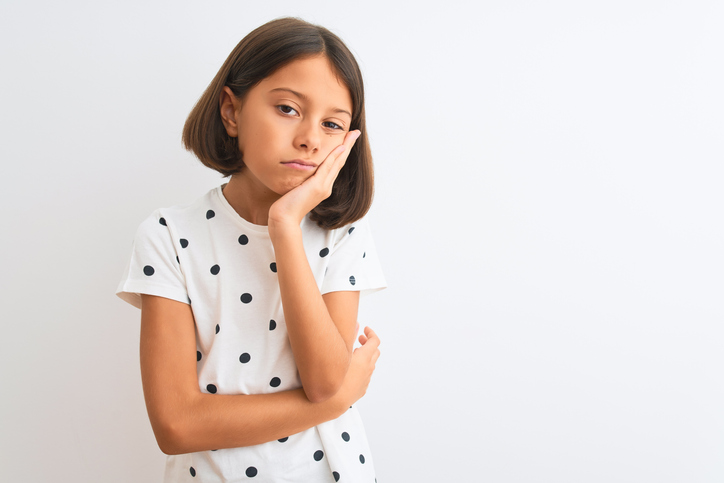 Adolescent girl standing and looking bored with her face resting on her hand