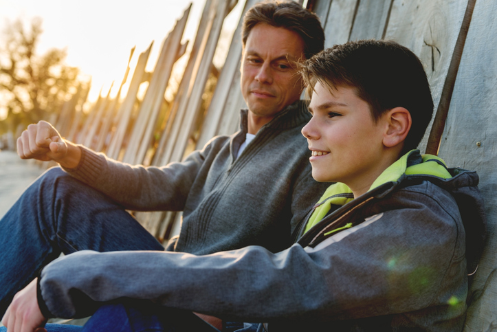 Father sitting with his son with ADHD outside, calm and having an important conversation