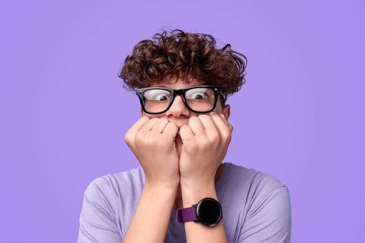 Teen kid with ADHD having anxiety and looking nervous in front of a bright purple background