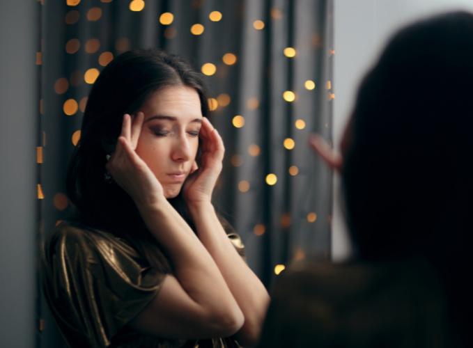 Teen at a holiday party closing her eyes and holding her hands up to her face like she's stressed out