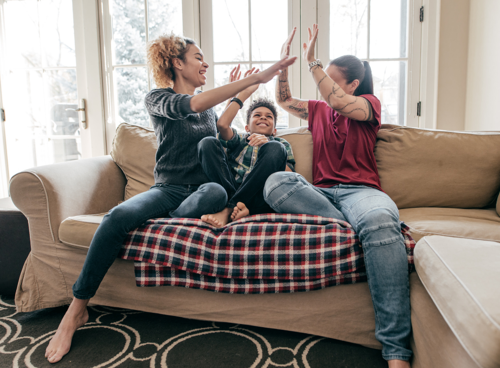 family of three giving each other a high five on the couch