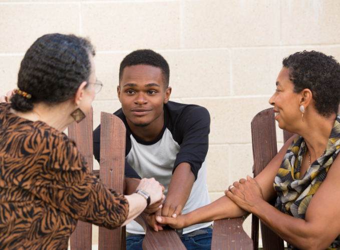 Teen talking and smiling with two elders, and holding their hands together
