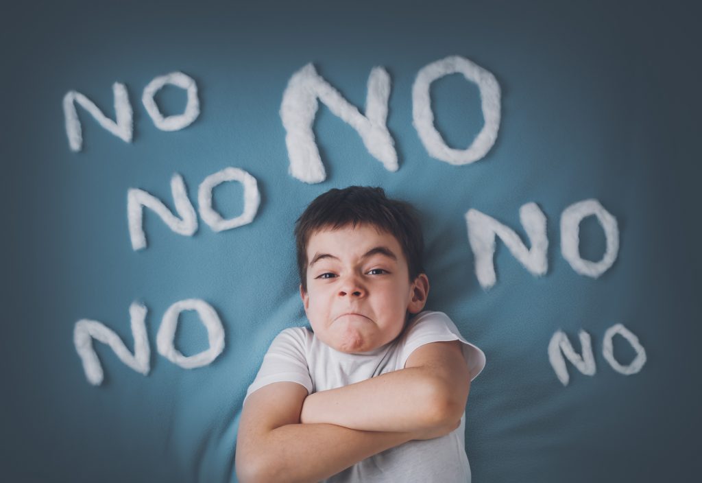 Bad boy on blue blanket background. Angry child with the word "NO" around him.