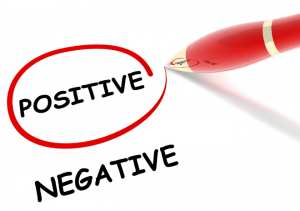 A paper with the words "positive" and "negative" on it, with a red pen circling "positive."