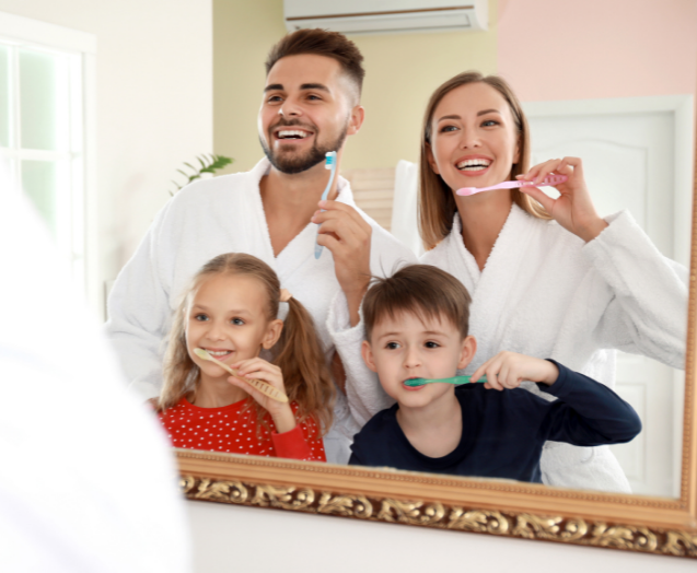 Family of four brushing their teeth together