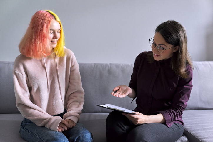 Therapist working with young adult client with brightly colored hair
