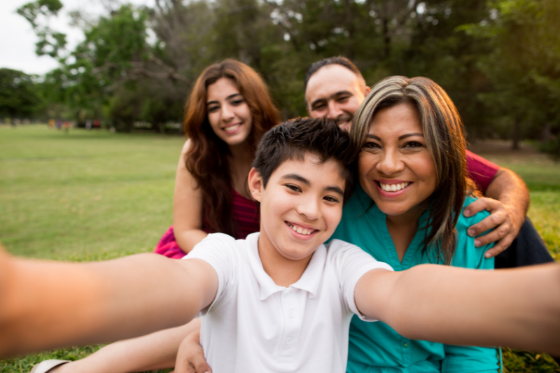 young boy taking selfie with sister and parents in the park