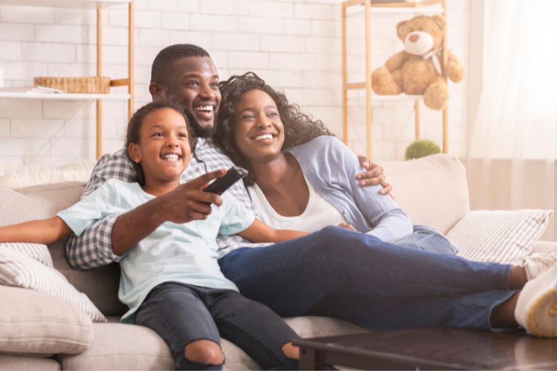 African American family smiling and watching tv together