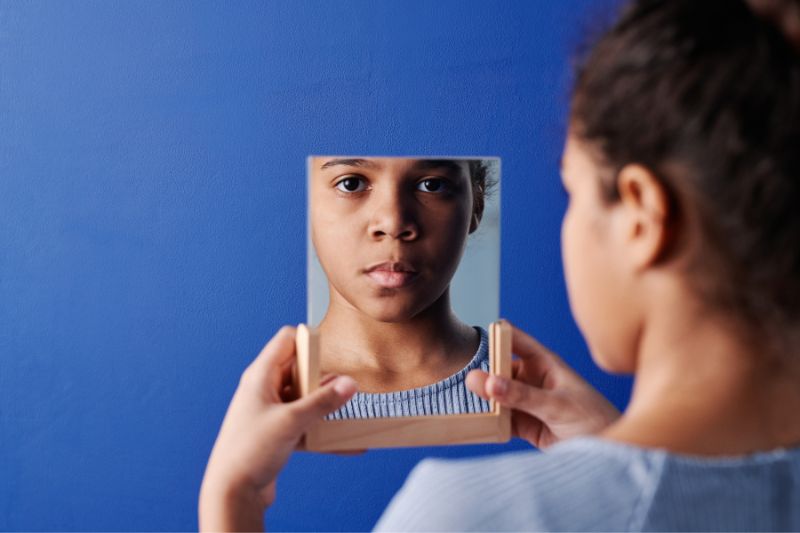 Brown young girl looking in mirror