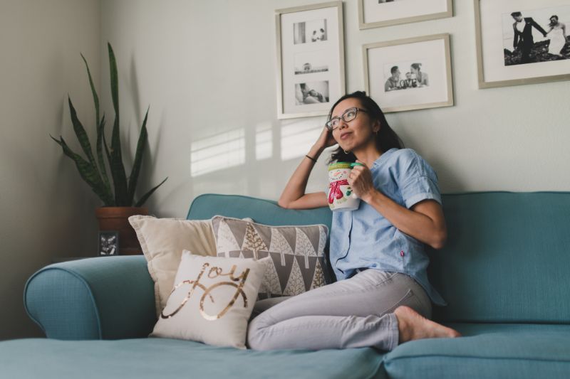 woman on sofa with mug deep in thought