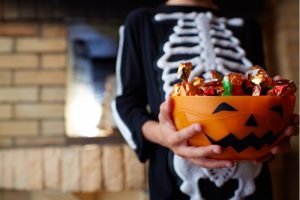 child holding bowl of Halloween candy