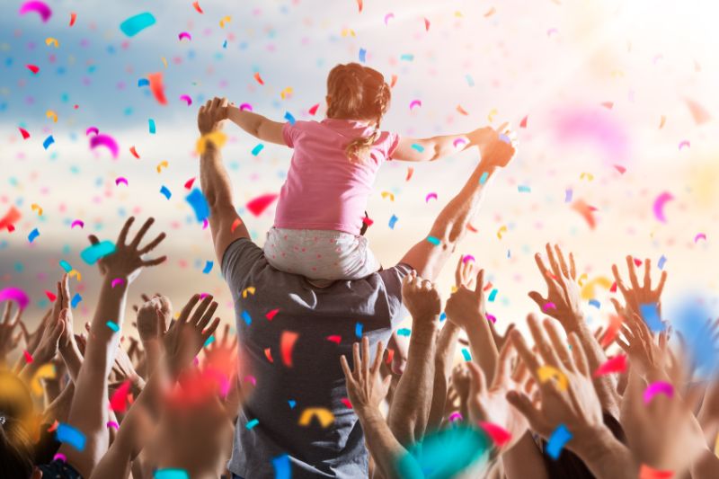 celebrating while child is on adult shoulders with confetti thrown