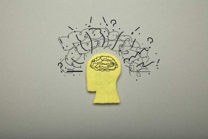 graphic of brain drawn inside yellow head with scribbles, question marks and exclamation points around it