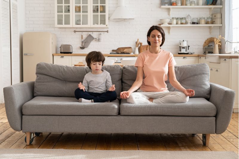 mother and child crossedlegged on couch meditating