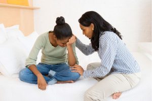 mother comforting upset teen daughter