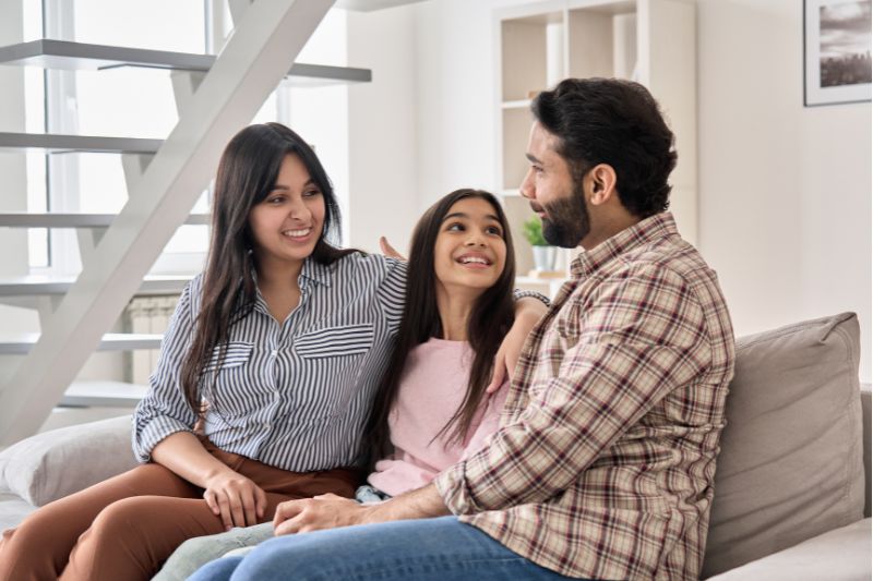 parents and teen daughter smiling on couch