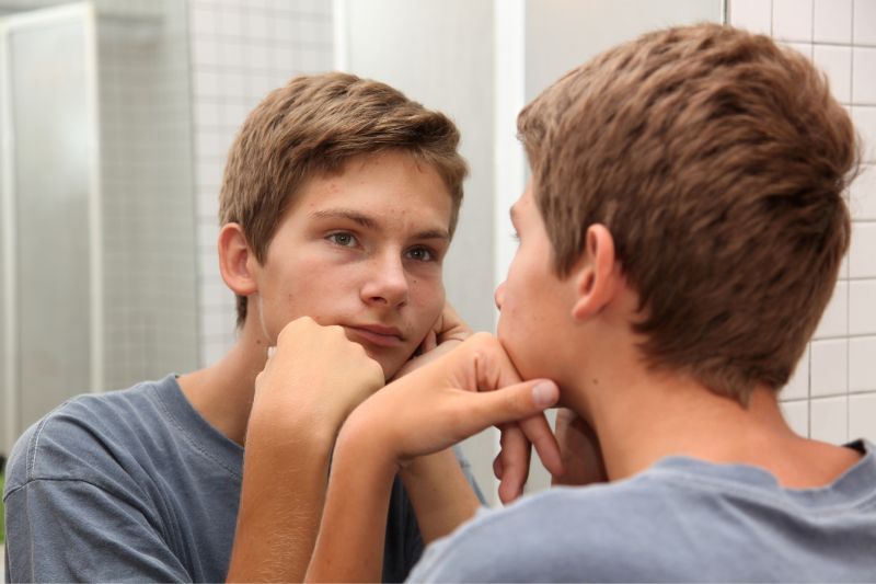 teen boy looking at himself in the mirror