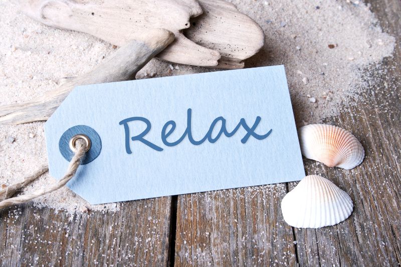 relax sign with sea shells and sand