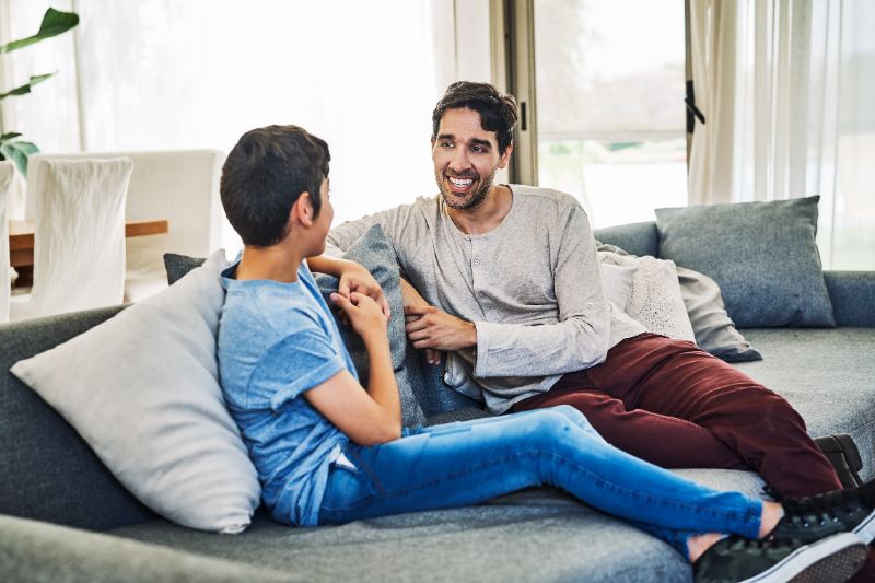 father and tween son talking on couch