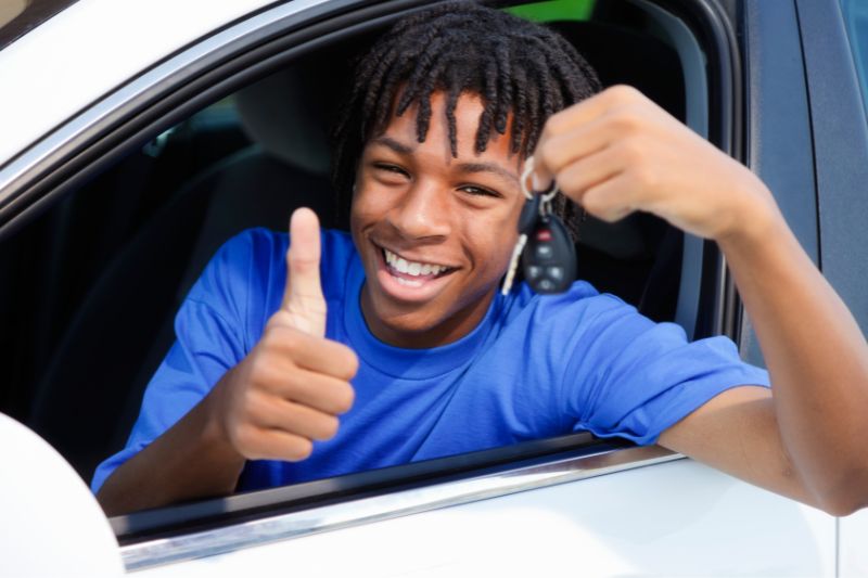 teen boy holding car keys thumbs up