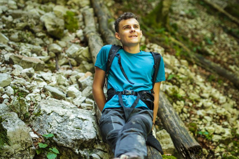 young man hiking in woods resting